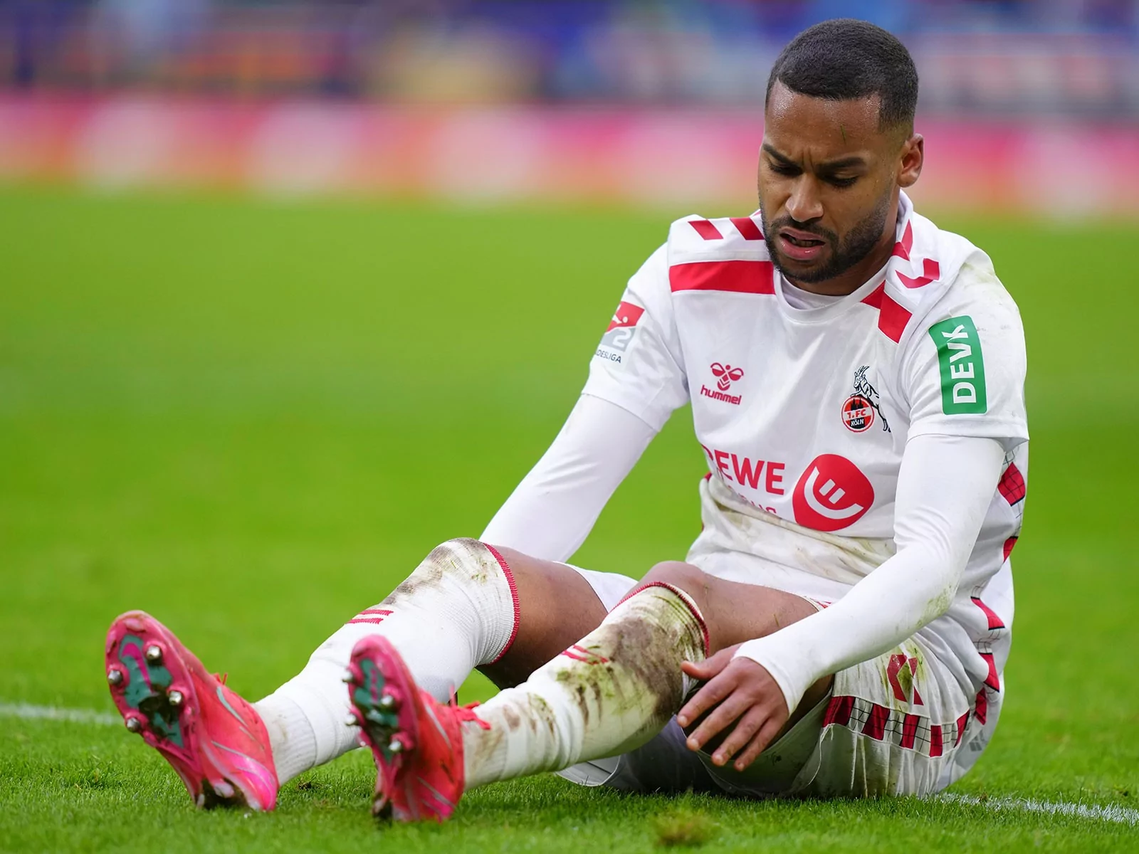 Linton Maina sitzt angeschlagen auf dem Boden bei einem Spiel des 1. FC Köln